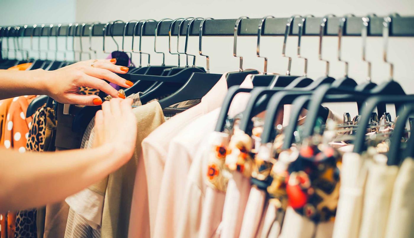 Woman's hands browsing a rack of clothes