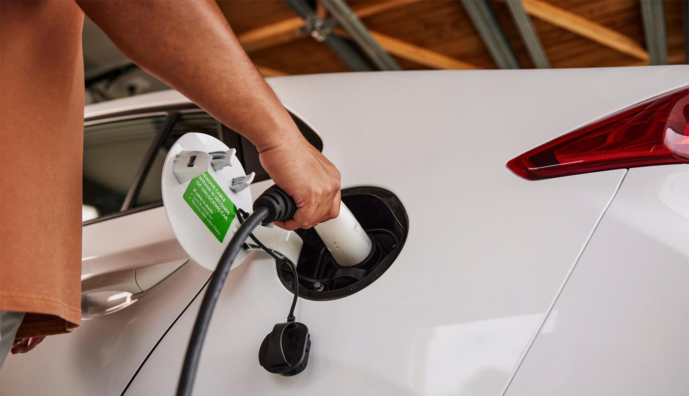 Man plugging charger into electric vehicle