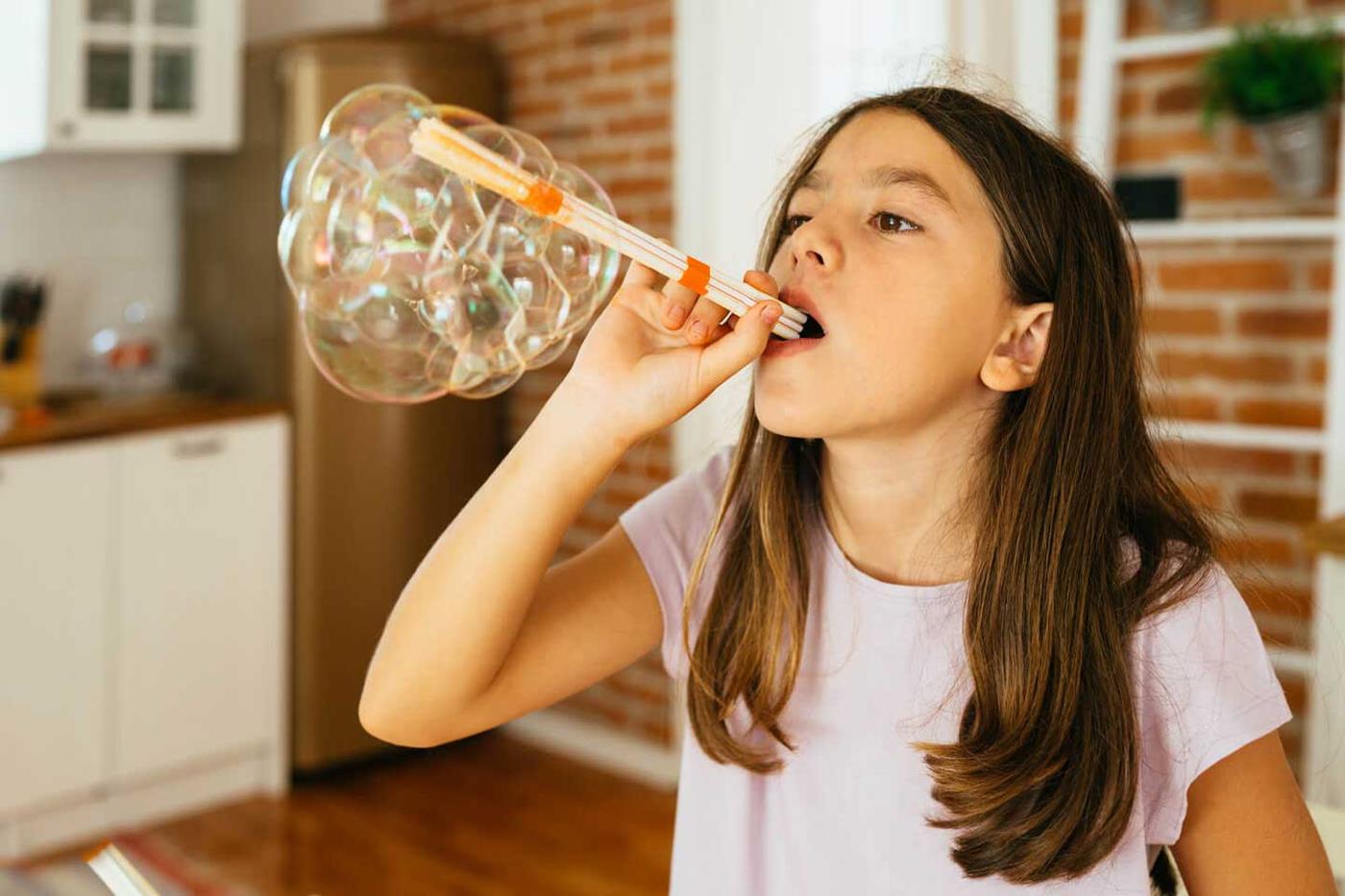 Student blowing bubbles in science experiment at home