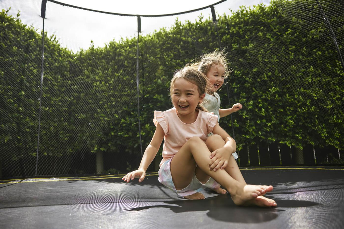Two young children playing on a trampoline