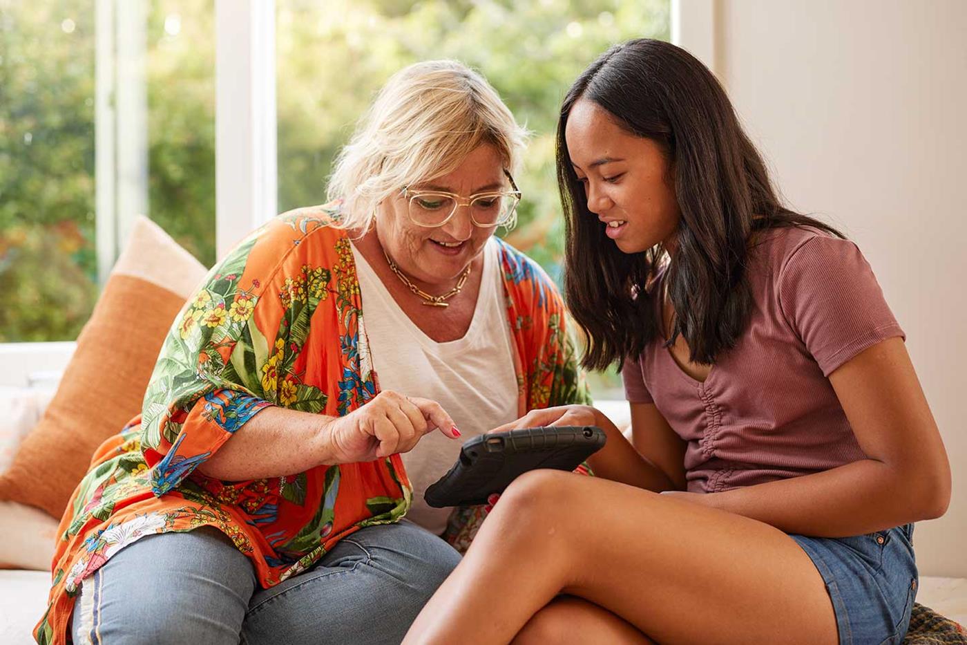 Child helping woman with ipad on a couch