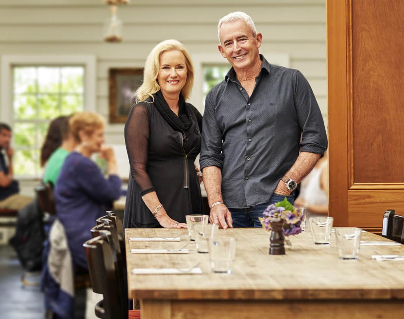 Two restaurant owners standing by a set table