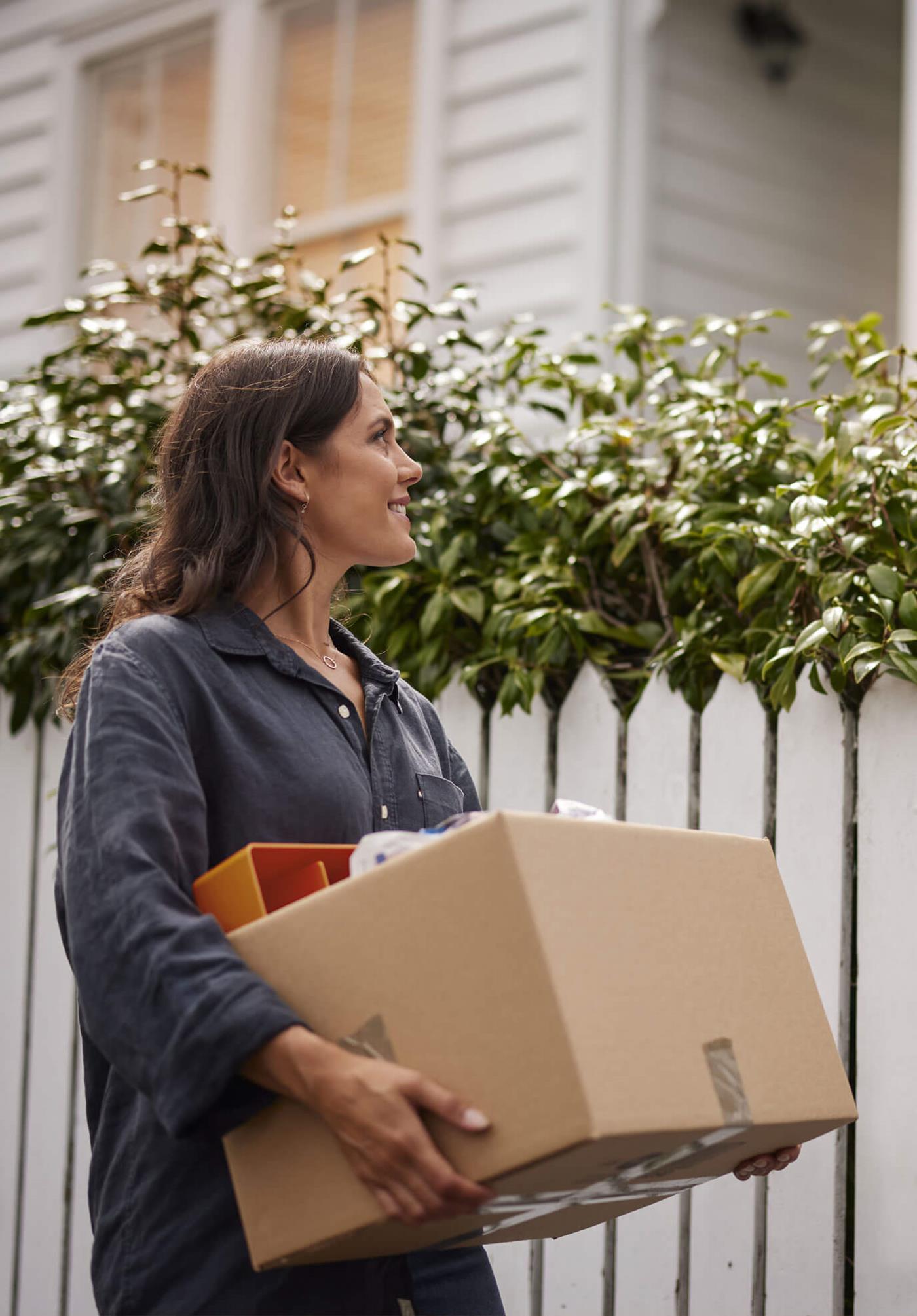 Woman outside home with moving box