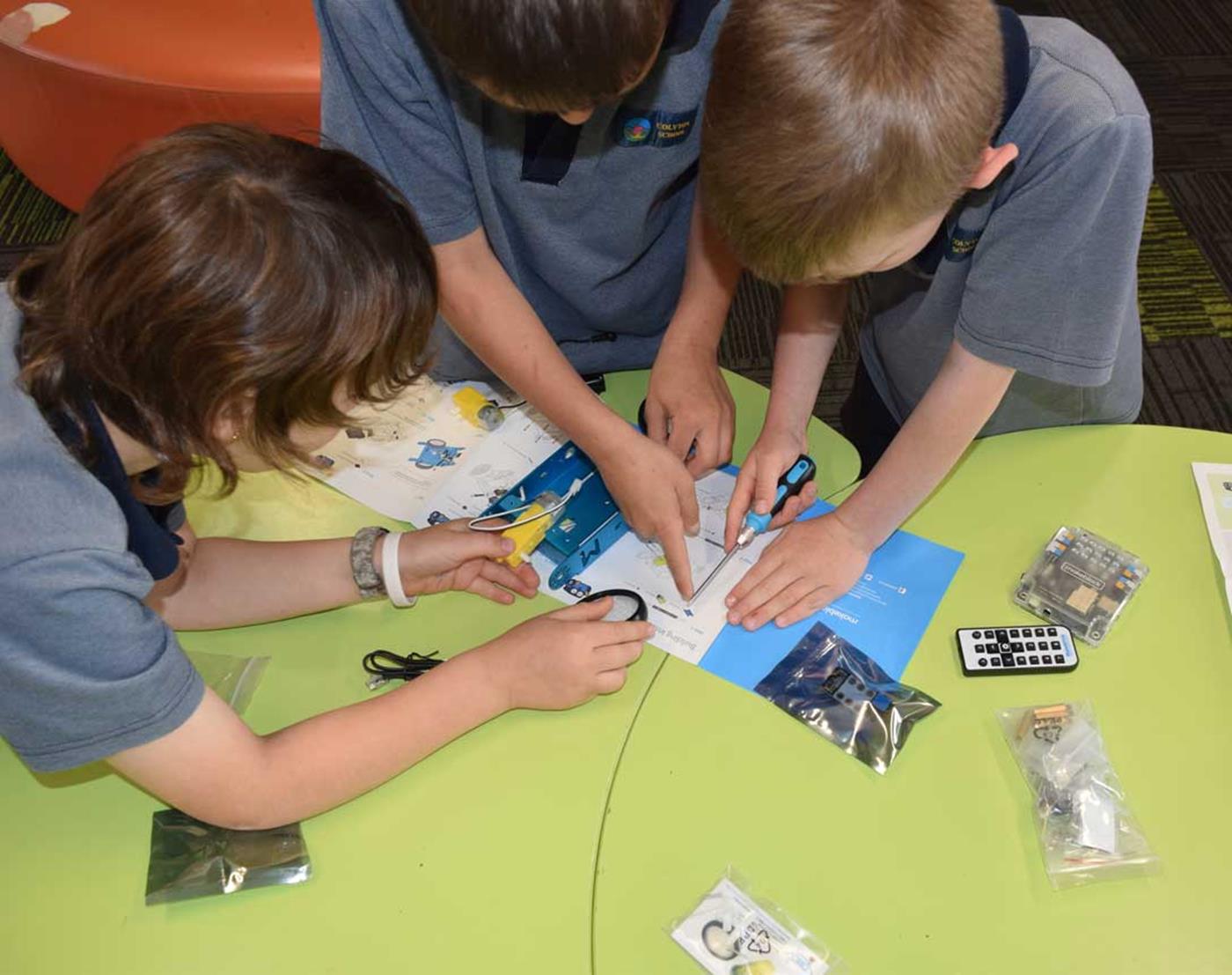 Three students building STEM project in classroom at school